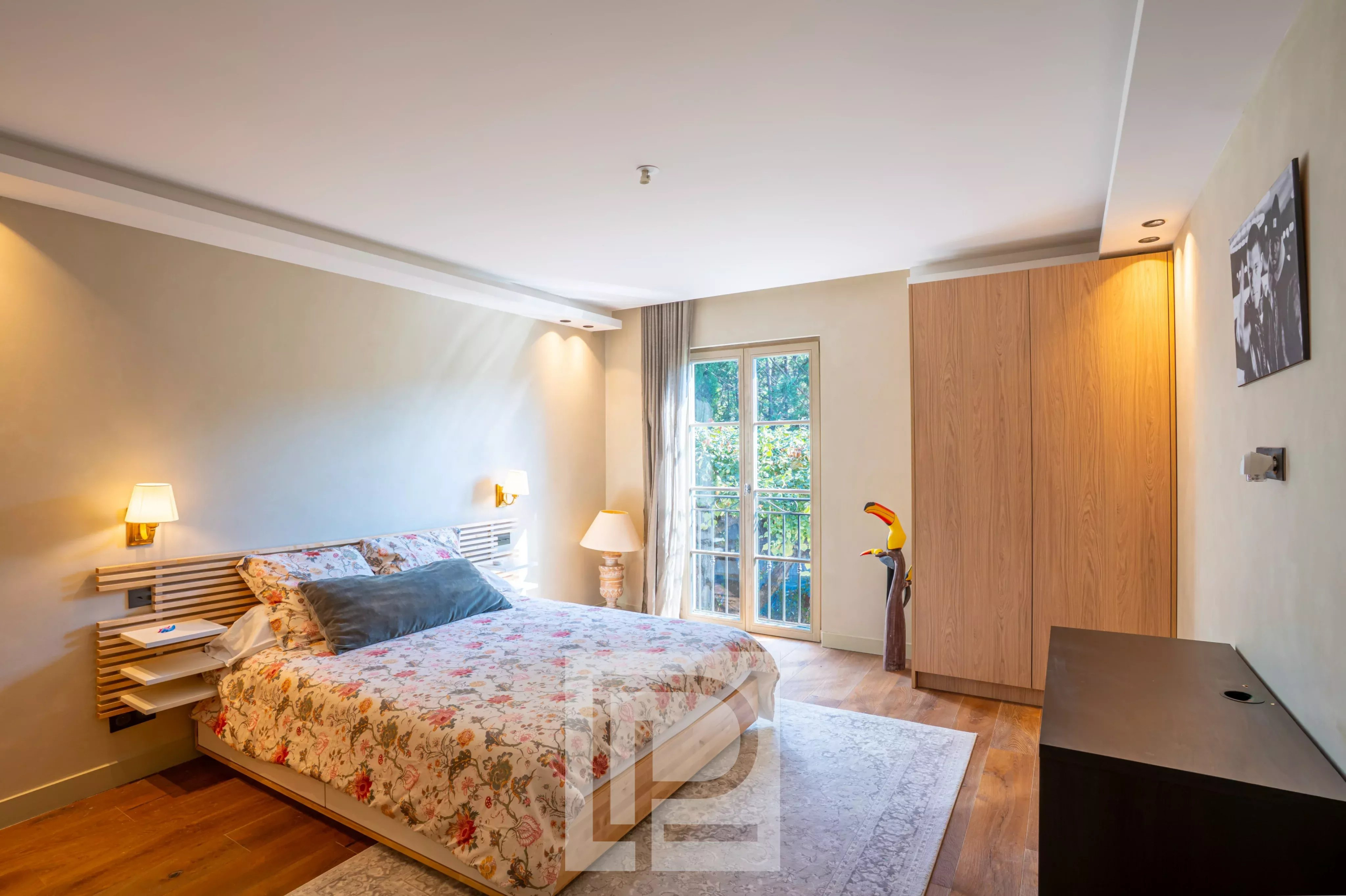 Chambre de bastide rénovée Chambre d'une bastide rénovée avec lit floral et fenêtre donnant sur un jardin.