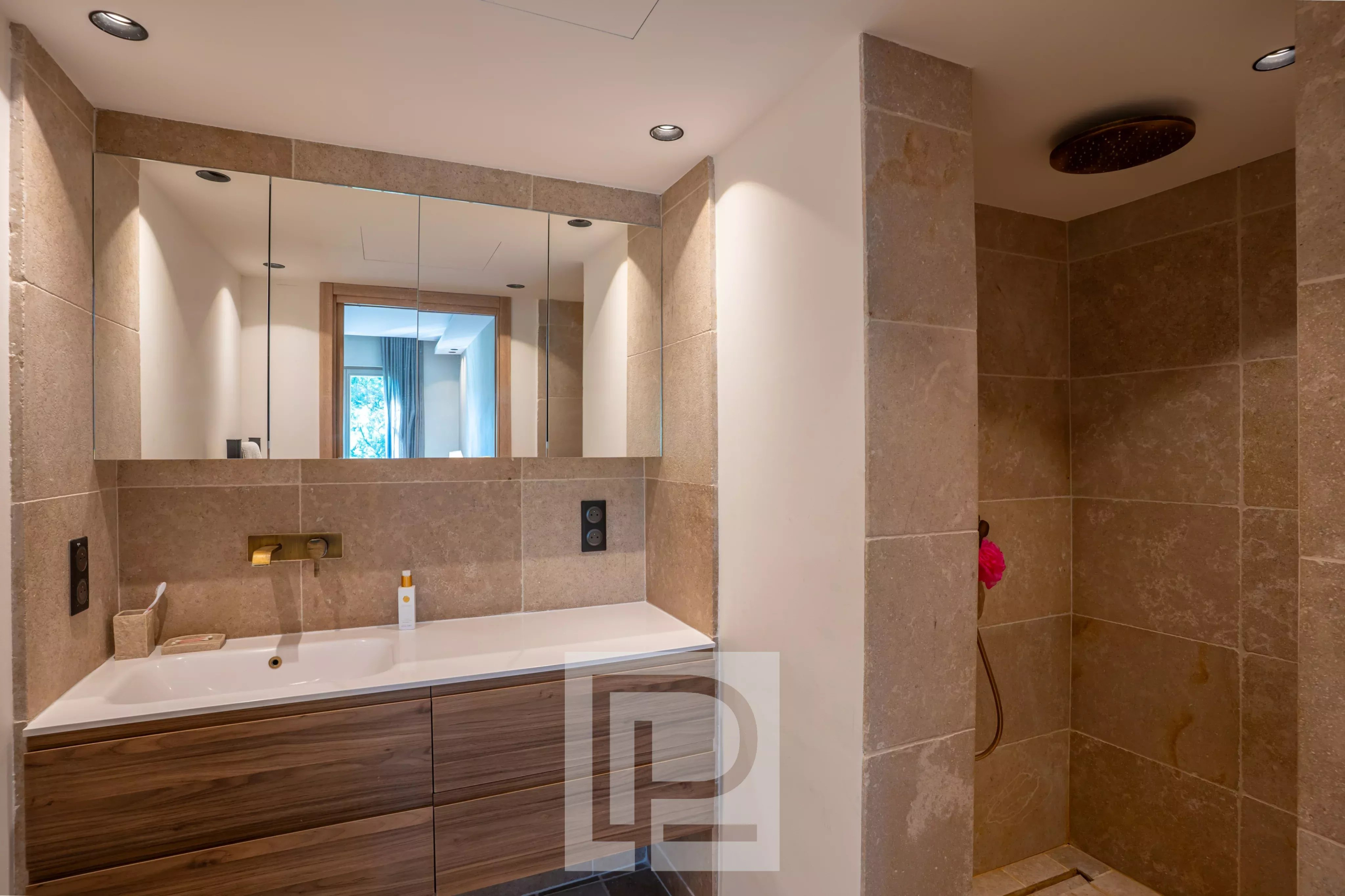 Salle de bain rénovée Salle de bain moderne avec douche et meuble en bois, murs en pierre beige.