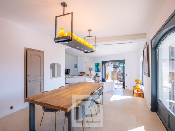 Intérieur d'une villa à Mougins avec une grande table en bois et des fenêtres lumineuses.