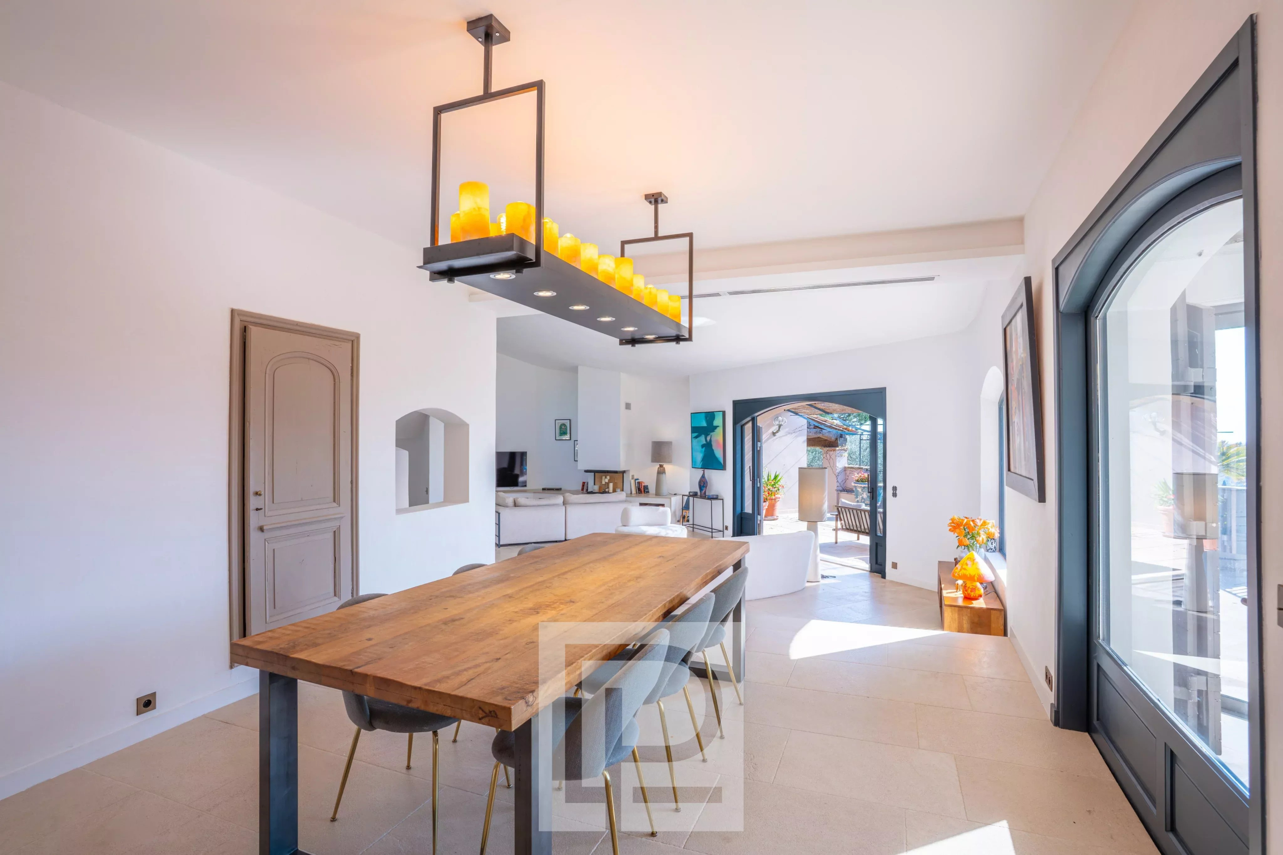 Intérieur d'une villa à Mougins avec une grande table en bois et des fenêtres lumineuses.