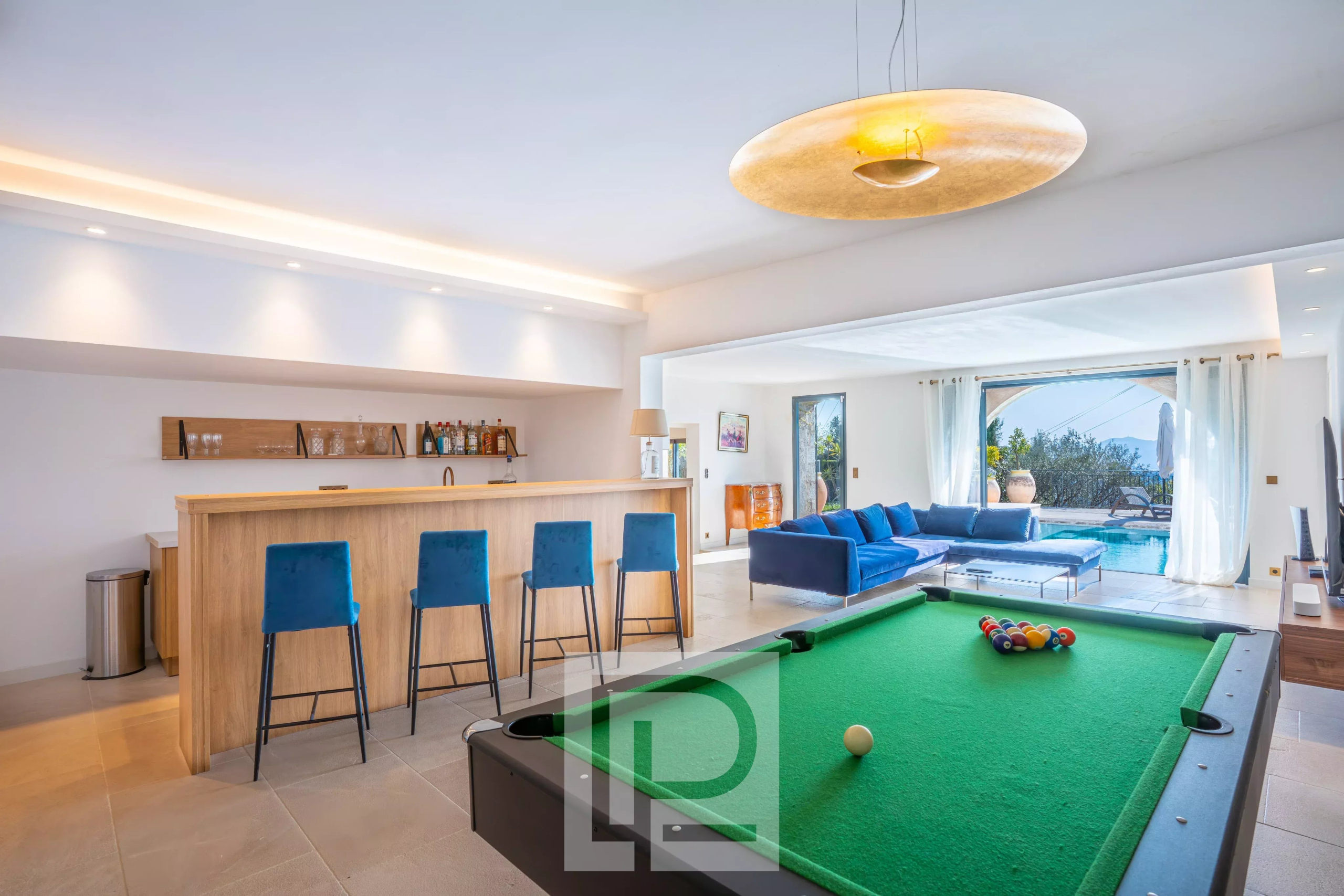 Intérieur d'une villa à Mougins avec billard, bar et salon lumineux.