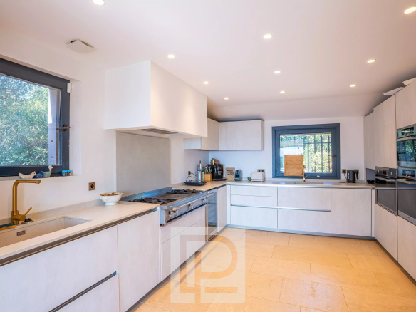 Cuisine moderne et lumineuse d'une villa à Mougins, avec équipements contemporains et fenêtres donnant sur l'extérieur.
