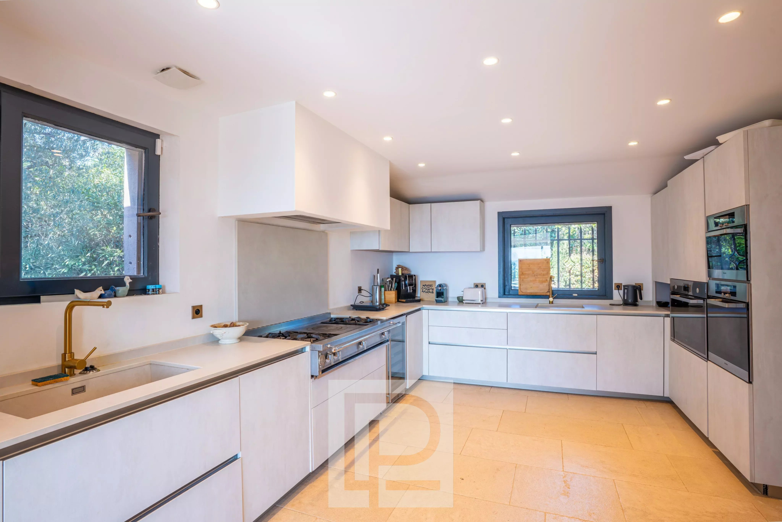 Cuisine moderne et lumineuse d'une villa à Mougins, avec équipements contemporains et fenêtres donnant sur l'extérieur.