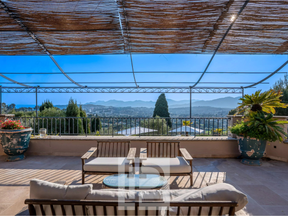 Terrasse avec vue panoramique sur les collines et la mer, mobilier de jardin en bois.