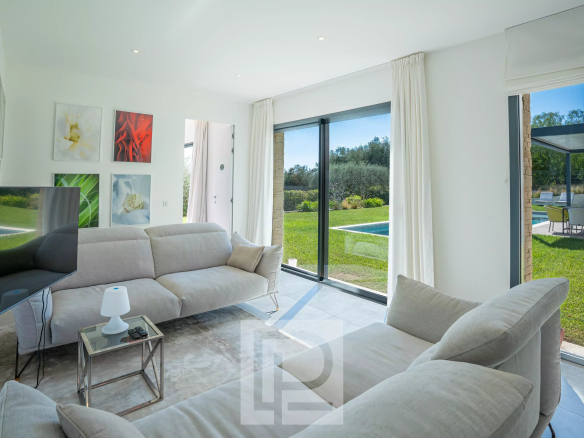 Intérieur d'une villa contemporaine à Roquefort-les-Pins avec un salon lumineux et accès au jardin.
