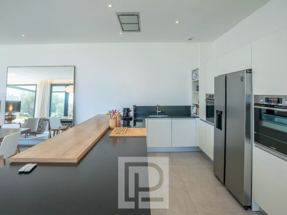 Intérieur moderne d'une villa contemporaine avec cuisine ouverte et plan de travail en bois à Roquefort-les-Pins.