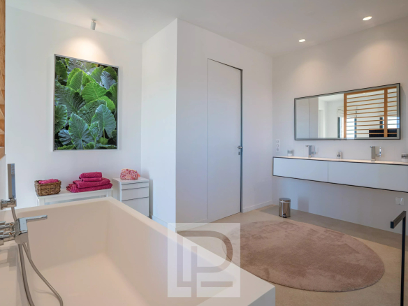 Salle de bain moderne avec baignoire, miroir et lavabo dans une villa contemporaine à Roquefort-les-Pins.