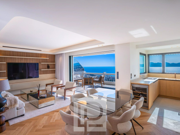 Intérieur lumineux d'un appartement à Cannes avec vue sur la mer, mobilier moderne et cuisine ouverte.