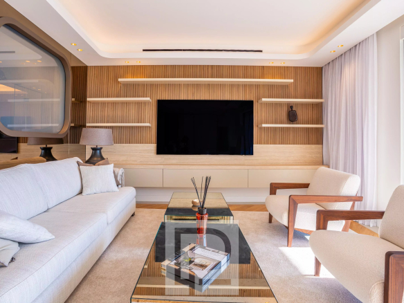 Salon lumineux d'un appartement moderne avec canapé, table basse et télévision murale.