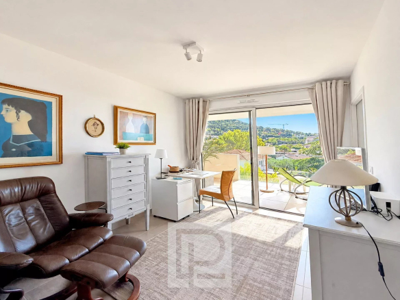 Salon lumineux d'un appartement avec vue sur les collines et la mer, mobilier moderne et accès à un balcon.