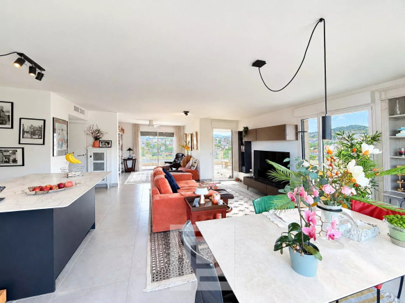 Intérieur d'un appartement moderne avec vue panoramique sur les collines et la mer, salon et cuisine ouverts.