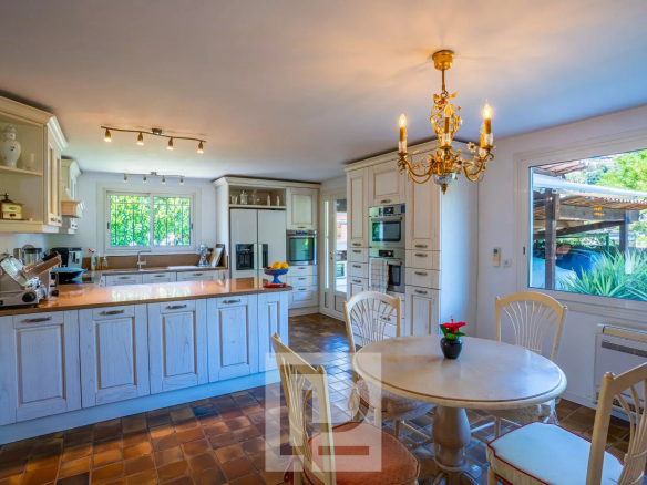 Cuisine lumineuse d'une maison familiale à Cannes, avec table et chaises, vue sur l'extérieur.