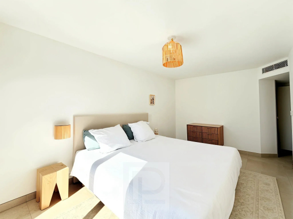 Chambre d'un appartement avec lit double et décoration minimaliste, lumière naturelle.