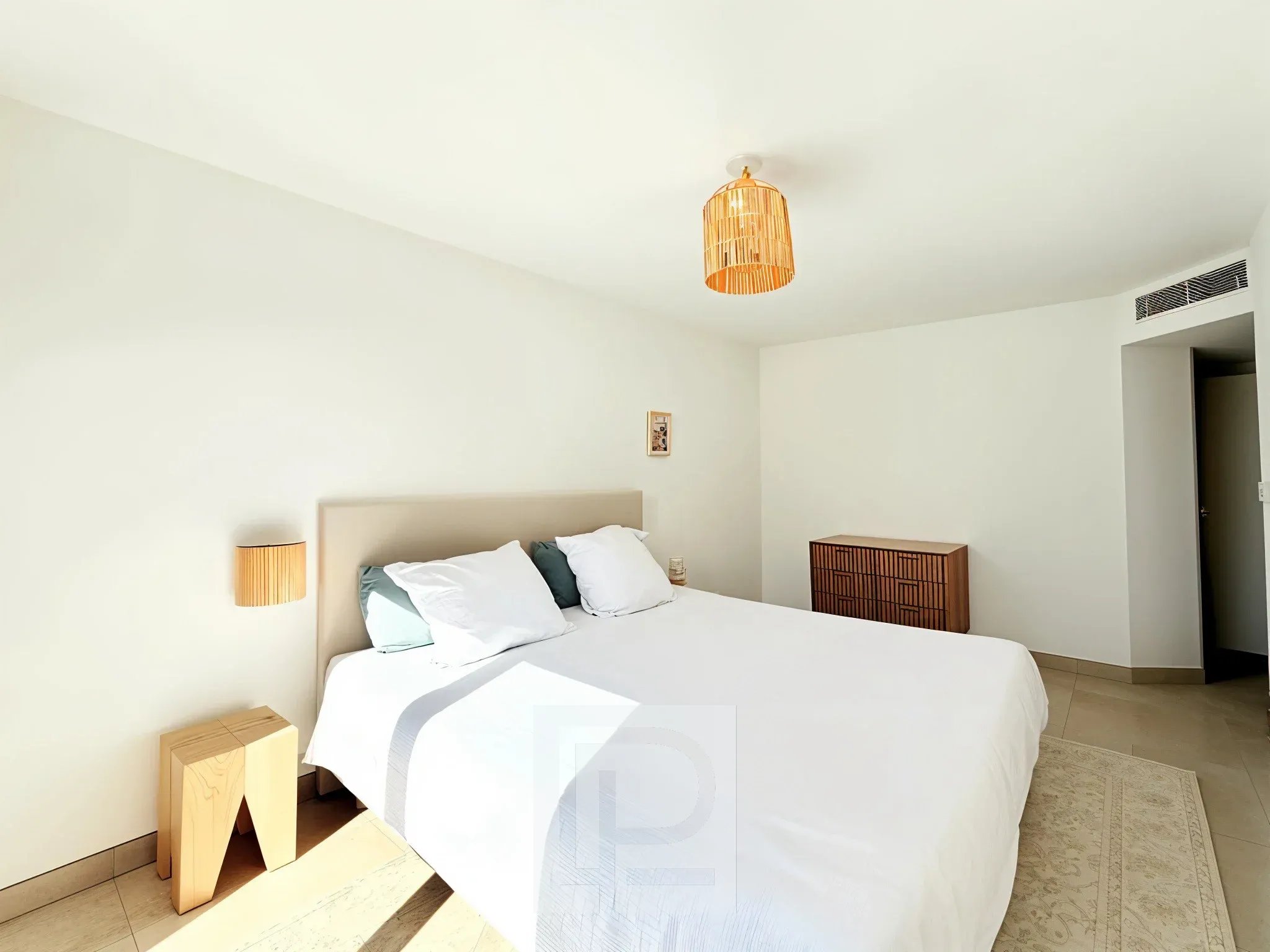 Chambre d’appartement à Mougins Chambre d'un appartement avec lit double et décoration minimaliste, lumière naturelle.