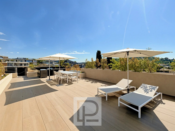 Terrasse ensoleillée avec chaises longues et parasols, vue sur un domaine résidentiel à Mougins.