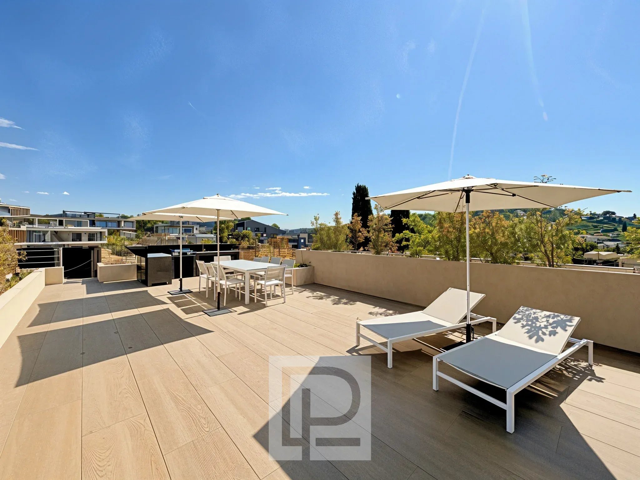 Terrasse privative avec vue à Mougins Terrasse ensoleillée avec chaises longues et parasols, vue sur un domaine résidentiel à Mougins.