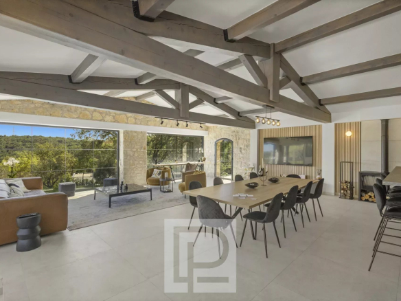 Intérieur d'une villa en pierre rénovée à Valbonne, avec une grande salle à manger et un salon lumineux.