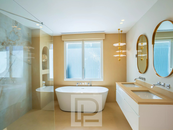 Salle de bain moderne avec baignoire, double vasque et grandes fenêtres.