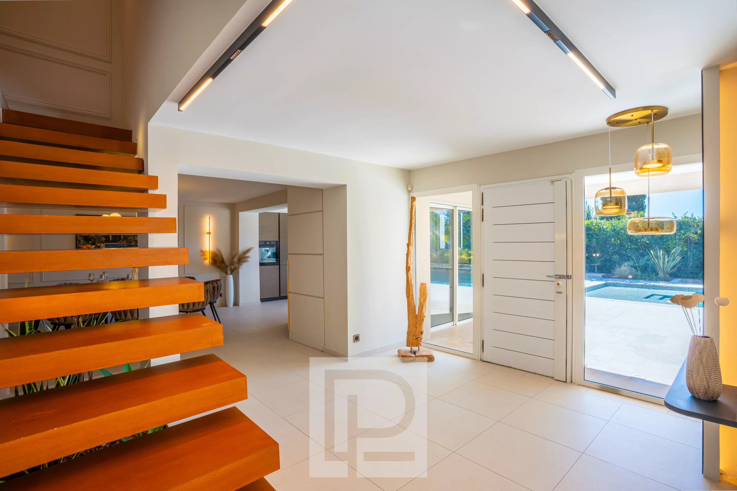 Intérieur d’une villa contemporaine à Mougins Intérieur d'une villa contemporaine avec escalier en bois et grandes fenêtres donnant sur l'extérieur.