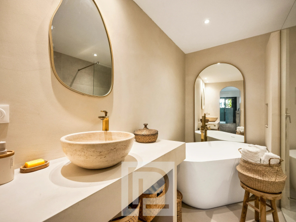 Salle de bain moderne avec baignoire, vasque et miroir dans un appartement rénové.