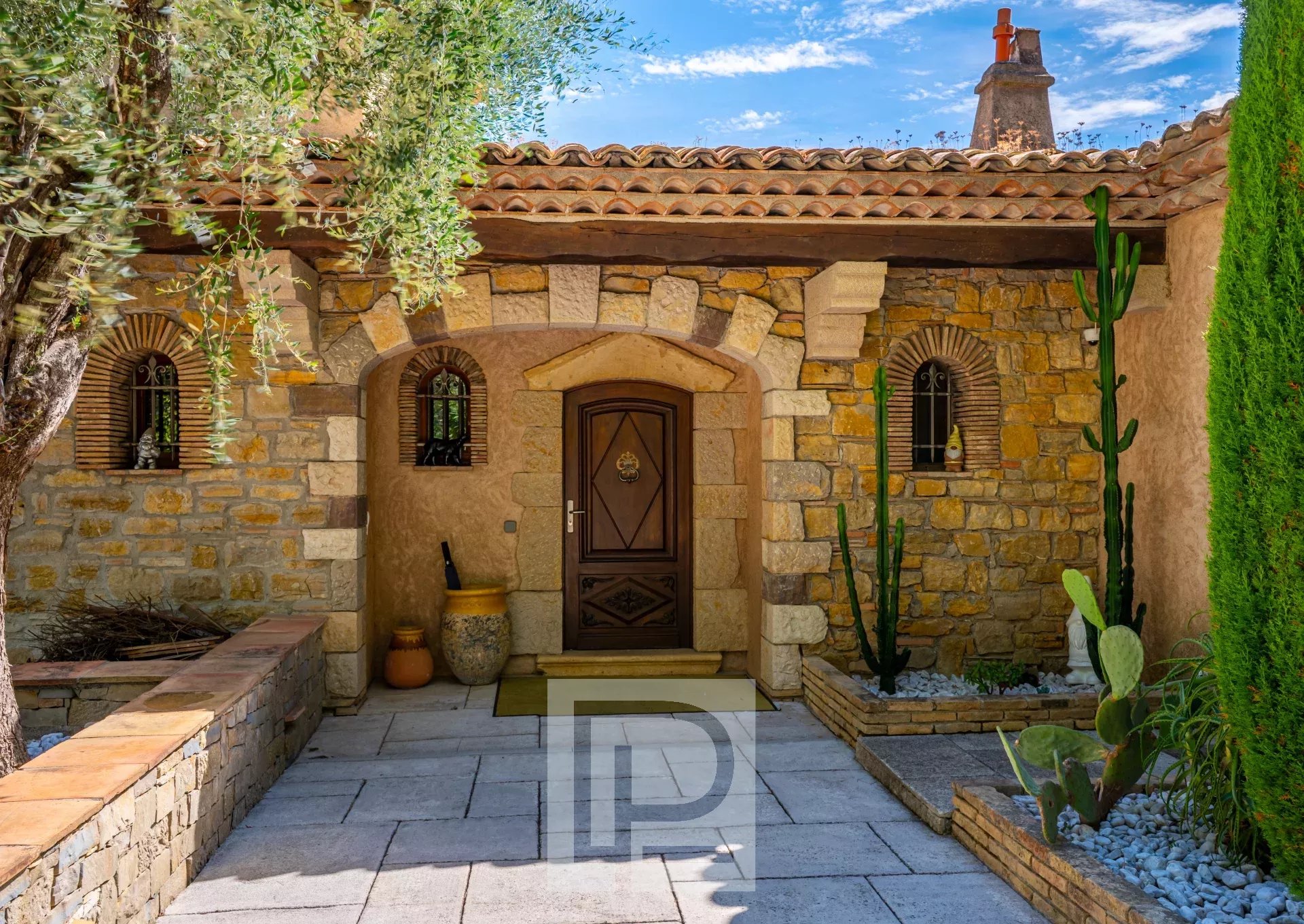 Entrance to a stone villa Entrance to a stone property with plants and a flagstone path, located in Mouans-Sartoux.
