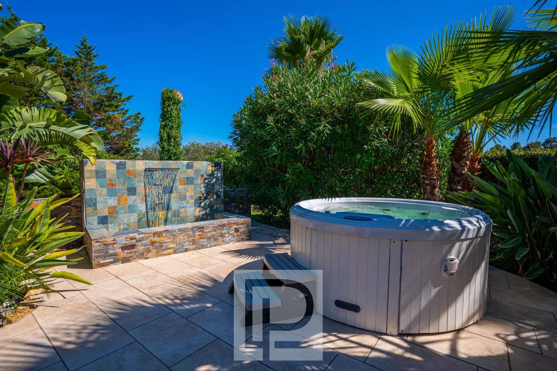 Outdoor area with jacuzzi Outdoor area of a property with jacuzzi and water wall, surrounded by lush vegetation.