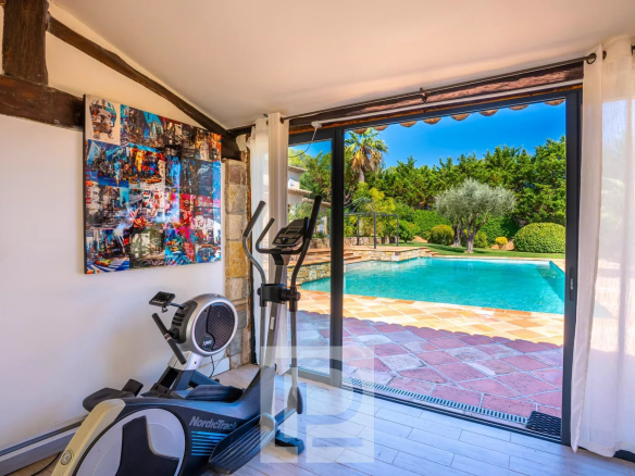 Interior of a villa with views of the pool and garden, fitness equipment visible.
