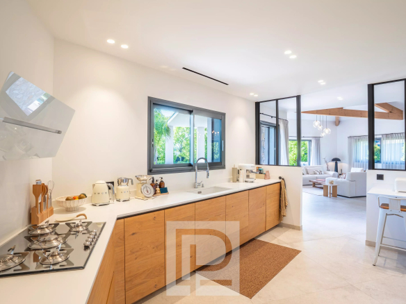 Cuisine moderne et lumineuse d'une villa contemporaine à Mougins, avec un plan de travail en blanc et des éléments en bois.