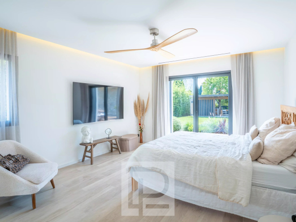 Chambre d'une villa contemporaine avec un lit, un fauteuil et une vue sur le jardin.