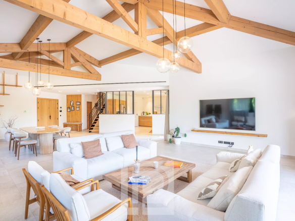 Intérieur d'une villa contemporaine avec salon lumineux et poutres apparentes.