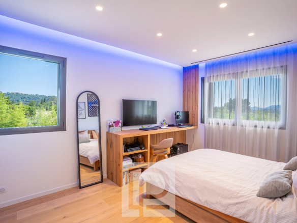Chambre moderne avec lit, bureau et vue sur la nature.