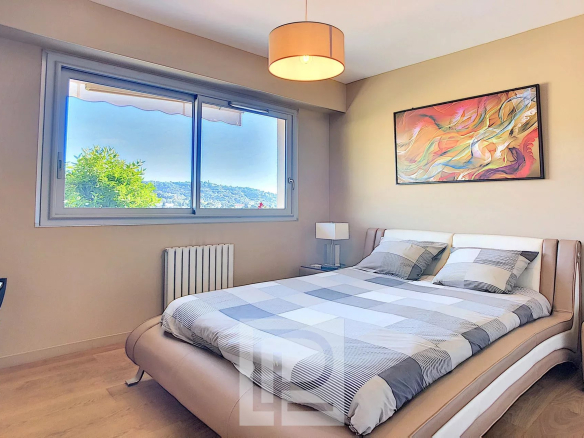 Chambre d'un appartement à Cannes avec lit double et fenêtre offrant une vue sur l'extérieur.