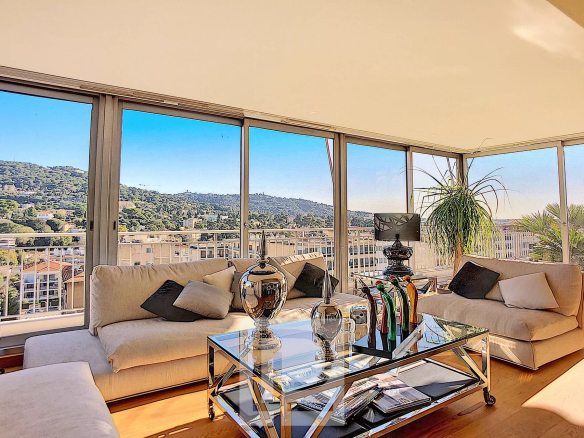 Salon lumineux avec vue sur les collines de Cannes, mobilier moderne et décoration élégante.