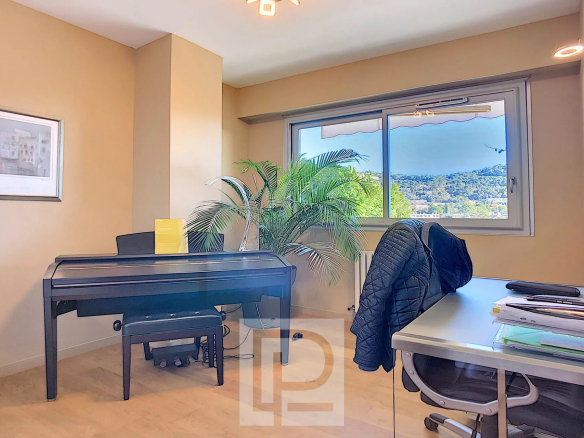 Intérieur d'un bureau lumineux avec un piano et une vue sur la nature à Cannes.