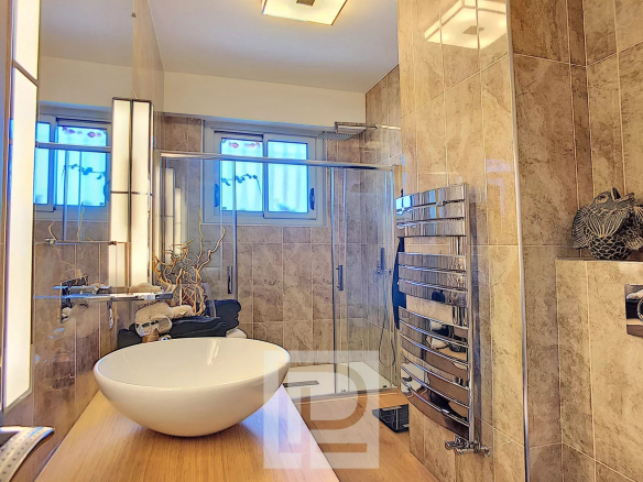 Salle de bain moderne avec baignoire sur pied et douche, décorée en marbre.