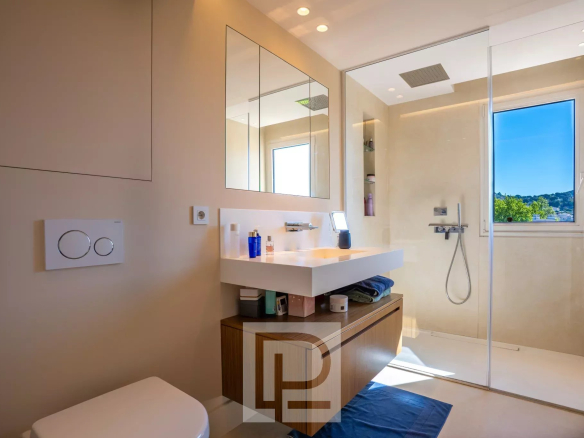 Salle de bain moderne avec douche, miroir et meuble en bois dans un appartement au Cannet.