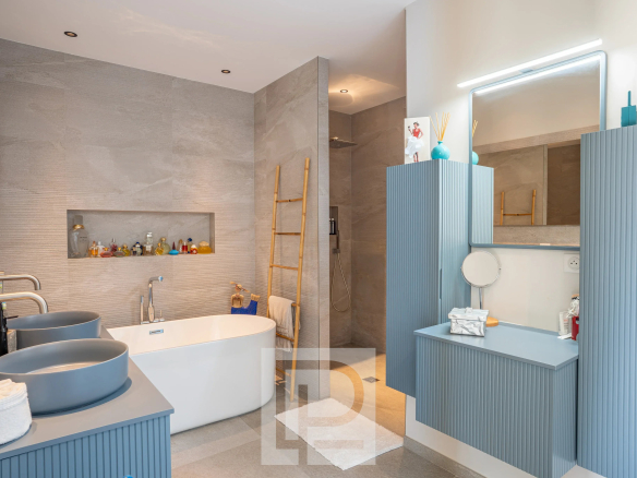Salle de bain moderne avec baignoire et meubles contemporains.