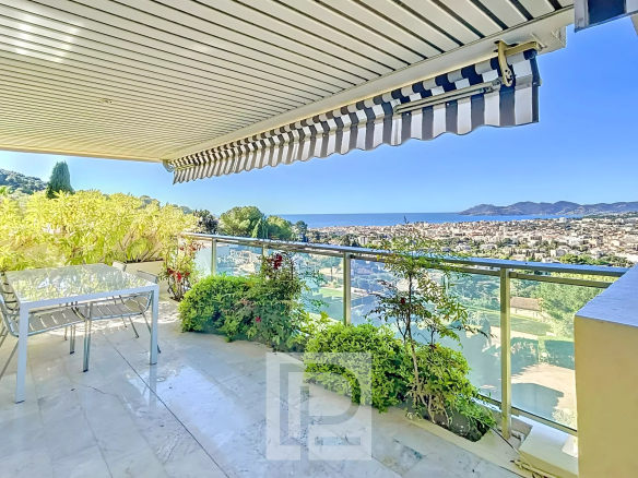 Terrasse d'un appartement avec vue panoramique sur la mer au Cannet, entourée de verdure.