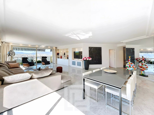 Intérieur d'un appartement lumineux avec salon et salle à manger, vue sur la mer.