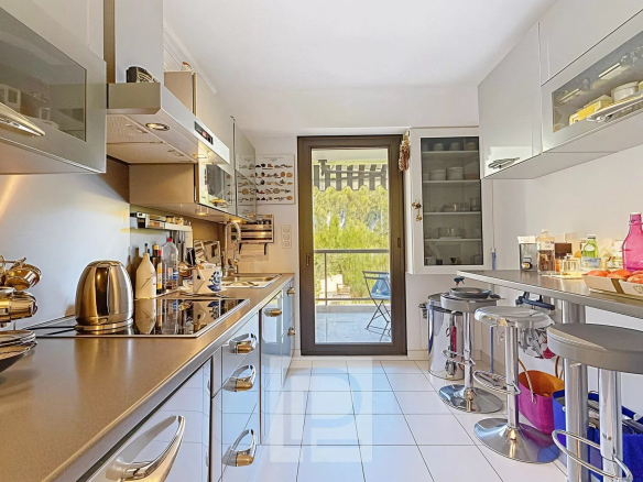 Modern and bright kitchen with access to a balcony overlooking greenery.