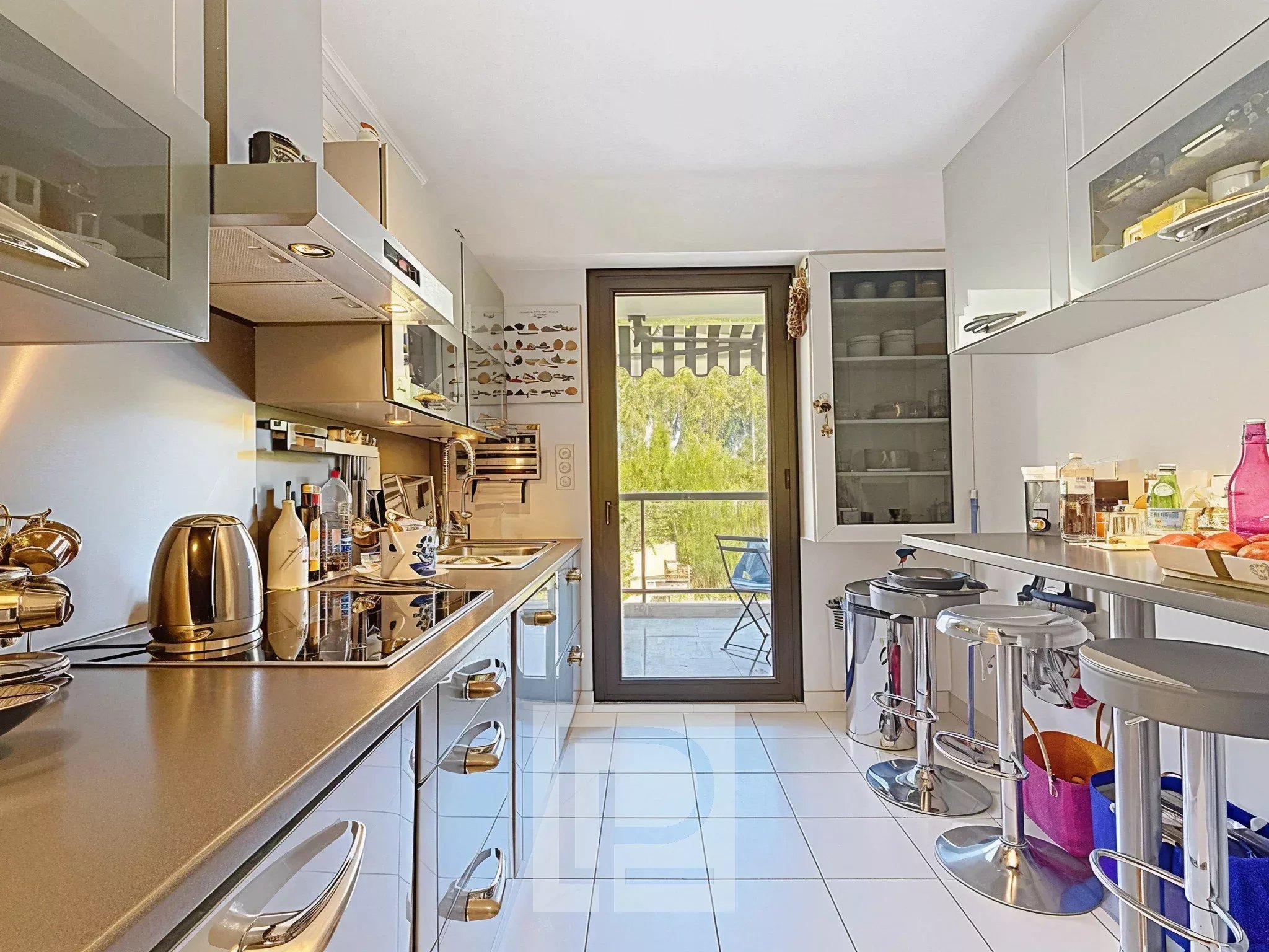 Kitchen of an apartment in Cannes Modern and bright kitchen with access to a balcony overlooking greenery.