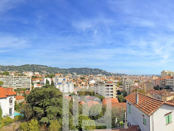 Panoramic view of Cannes with buildings and hills in the background.