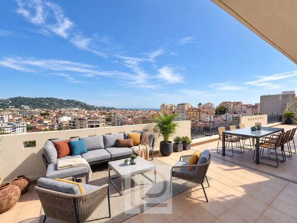 Terrace of an apartment in Cannes with views of the city and the sea, modern garden furniture.