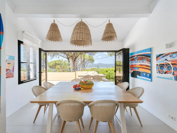 Salle à manger lumineuse avec vue sur la mer, décorée de tableaux, dans une villa à Gassin.