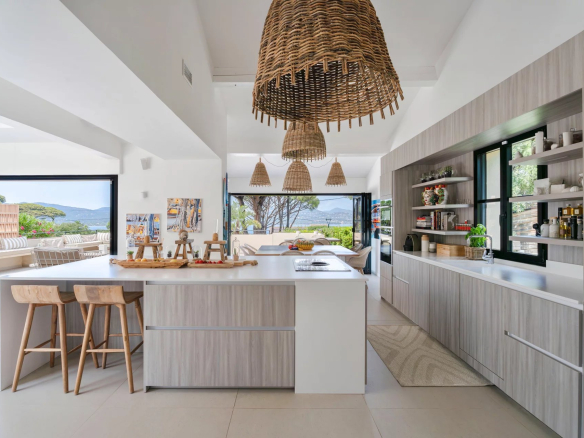 Cuisine moderne et lumineuse avec îlot central dans une villa à Gassin, vue sur mer.