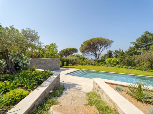 Vue de la piscine et du jardin d'une villa neuve à Sainte-Maxime avec vue sur la mer.