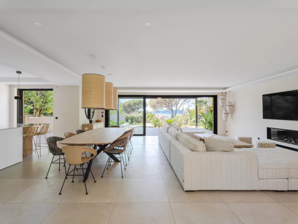 Intérieur d'une villa moderne avec salon, salle à manger et vue sur jardin.