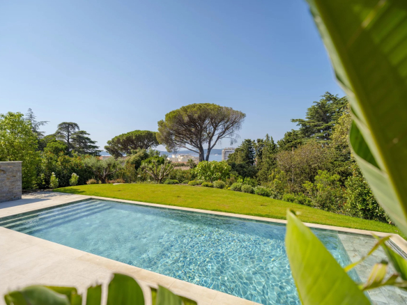 Vue de la piscine et du jardin d'une villa neuve à Sainte-Maxime avec vue sur la mer.