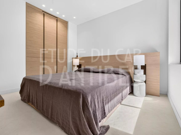 Chambre d'une villa moderne à Antibes avec lit et mobilier en bois.