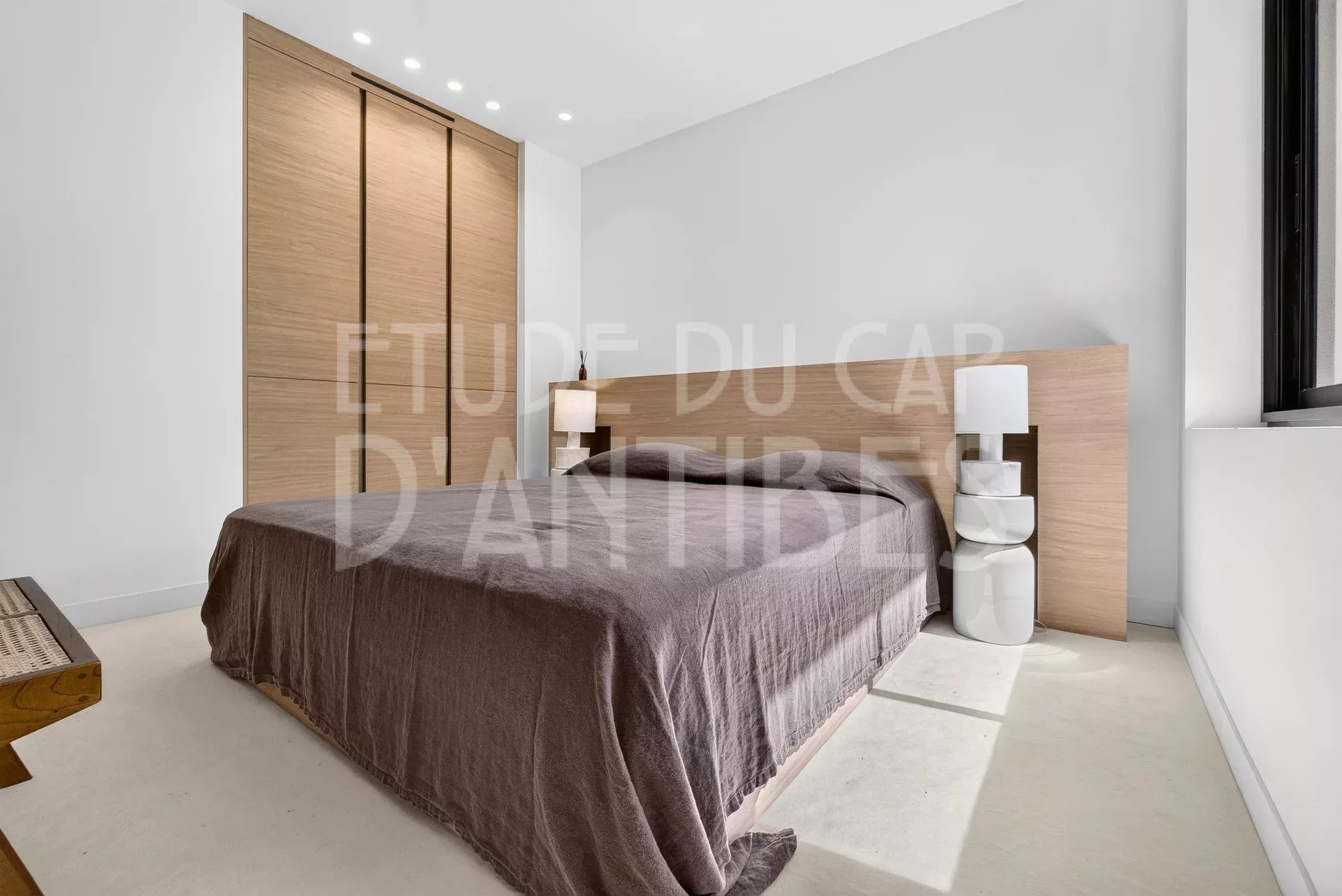 Chambre d'une villa moderne à Antibes avec lit et mobilier en bois.